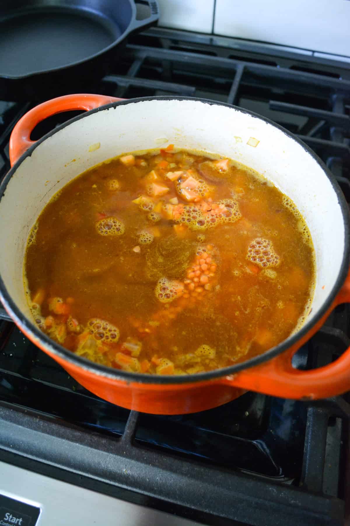 Sweet potato, red lentil and vegetable stock added into the pot.