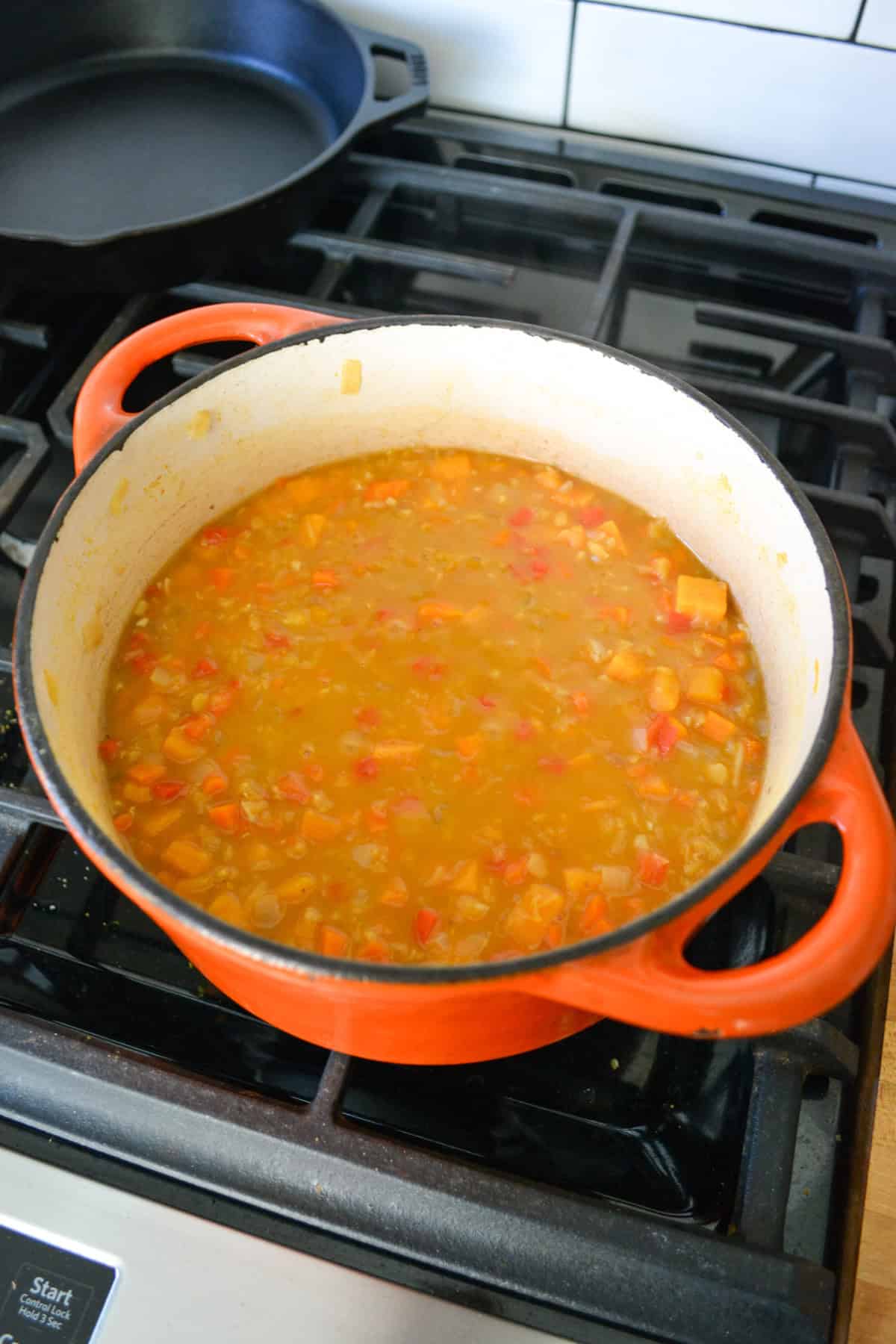 Simmering Carrot red lentil soup in a large Dutch oven.