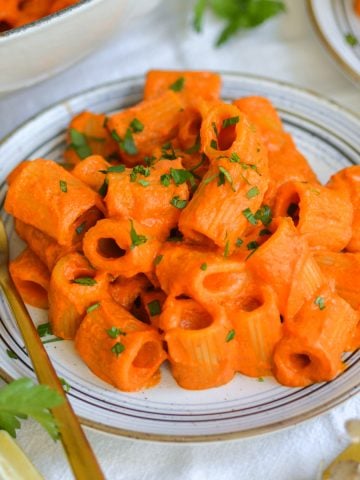 Creamy Harissa Pasta on a plate with a gold fork.