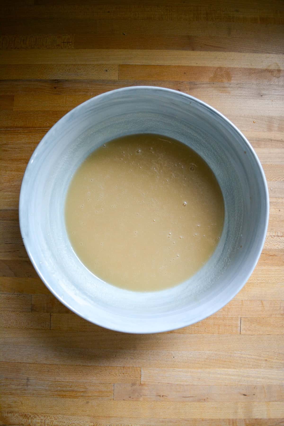 Wet ingredients for the cupcakes in a large marble bowl on a wooden surface.