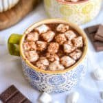 Vegan Oat Milk Hot Chocolate in a mug topped with marshmallows and shaved chocolate.