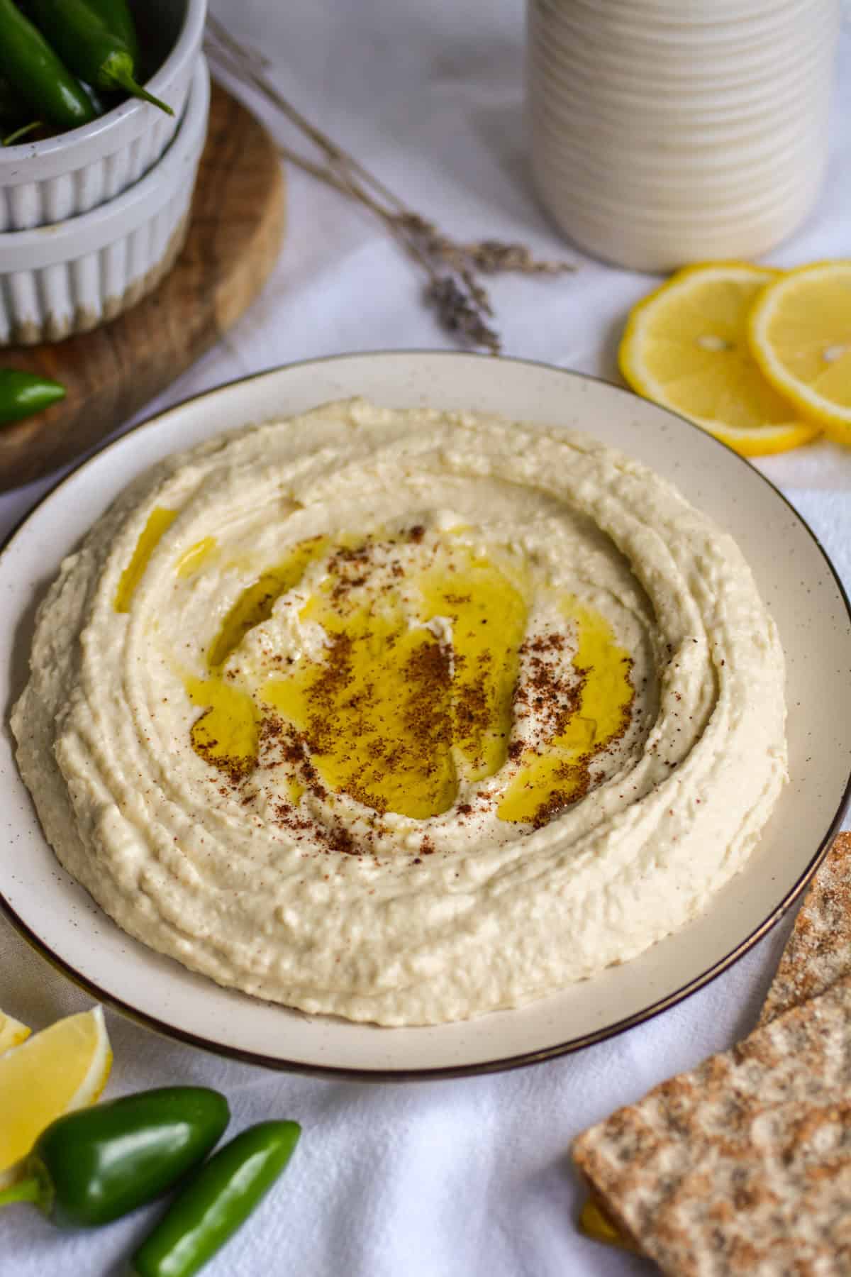 Butter Bean Hummus on a plate topped with olive oil on a white cloth.