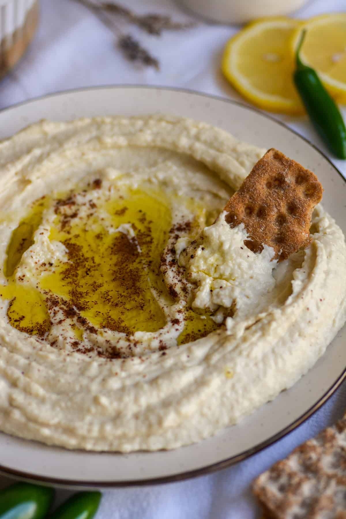 A cracker dipped into hummus on a plate.