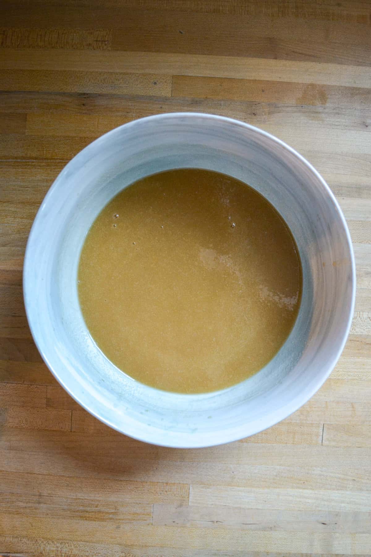 Wet ingredients in a large mixing bowl on a wooden surface.