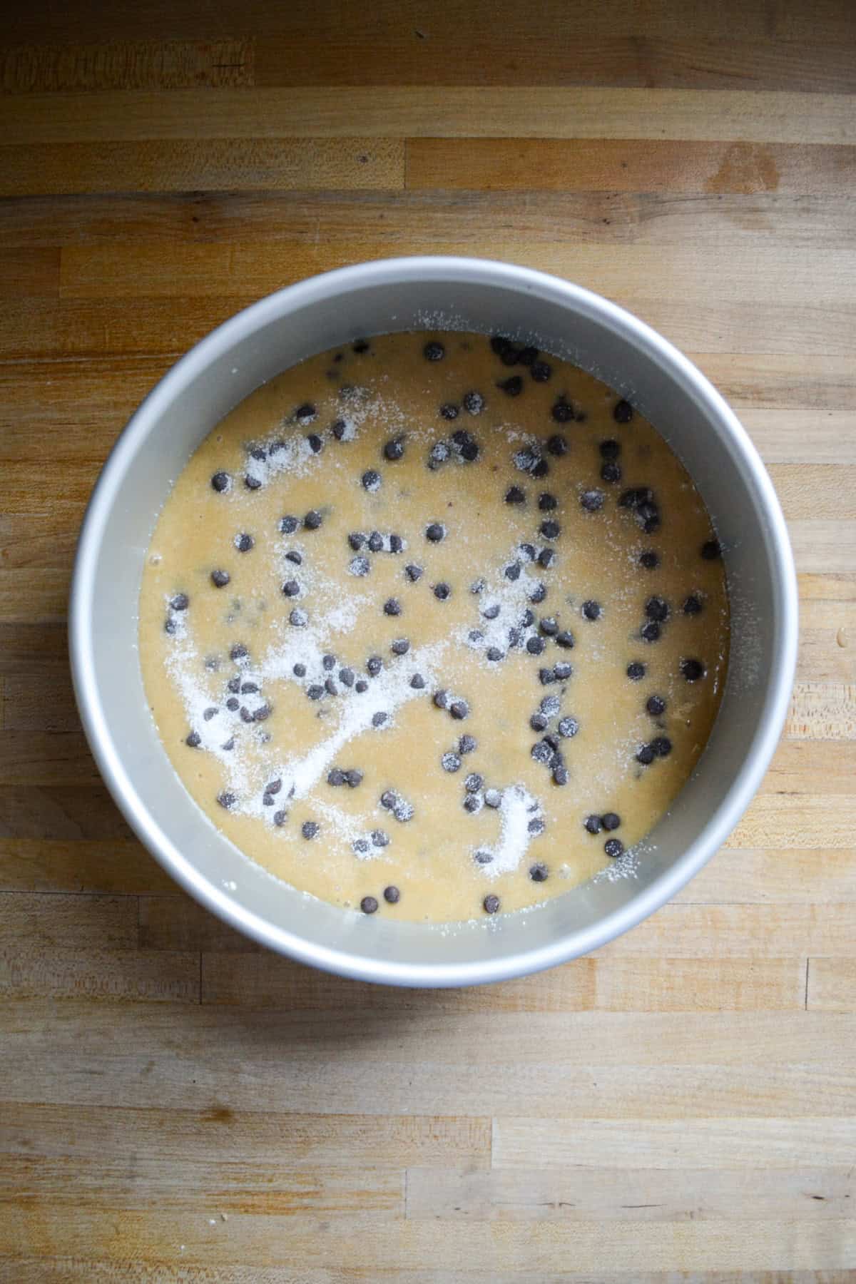 Chocolate chip cake batter in a round cake pan.