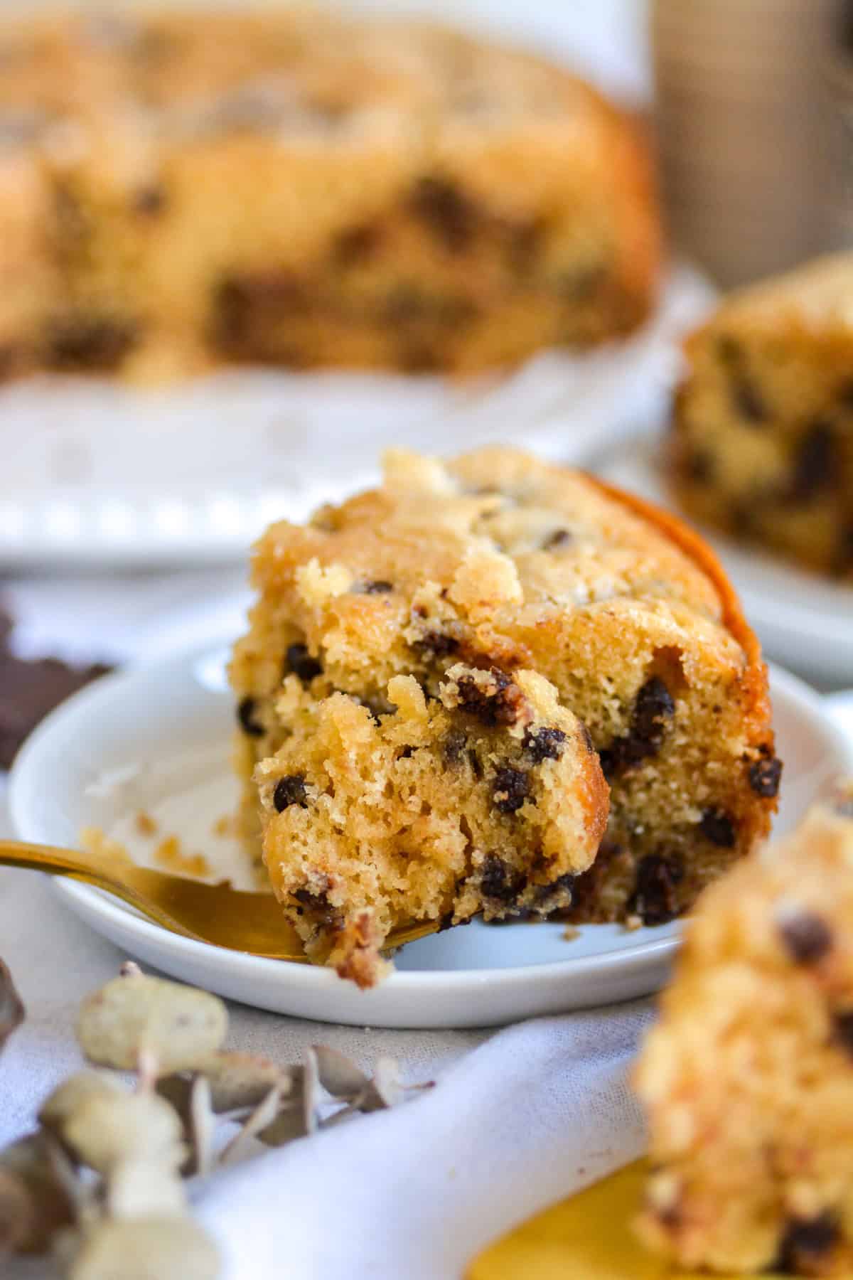 A bite of chocolate chip snack cake on a fork with a slice of cake behind it.