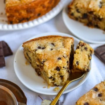 A slice of chocolate chip snack cake on a plate with a bite taken out of it.