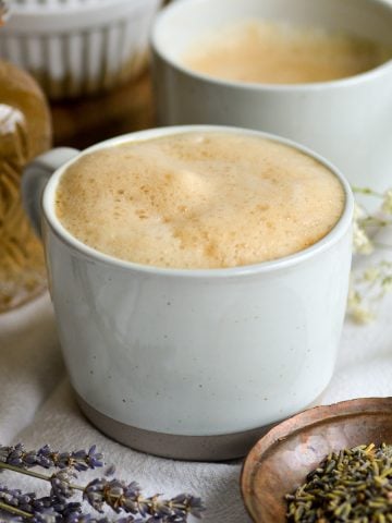 Lavender Oat Milk Latte in a mug with lavender flowers on the table.