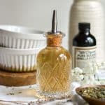 Lavender simple syrup in a glass bottle with a pour spout.