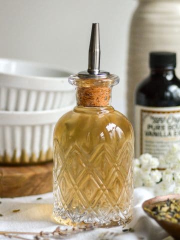 Lavender simple syrup in a glass bottle with a pour spout.