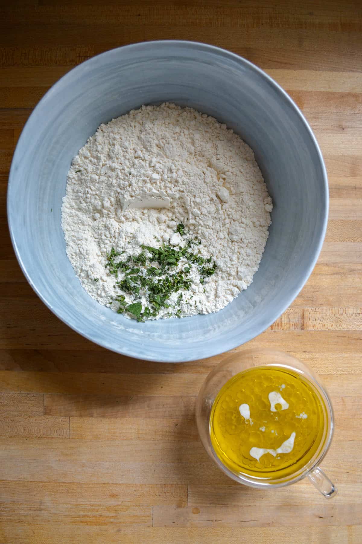 Dry ingredients for making the biscuit topping in a large bowl and the wet ingredients in a small cup.