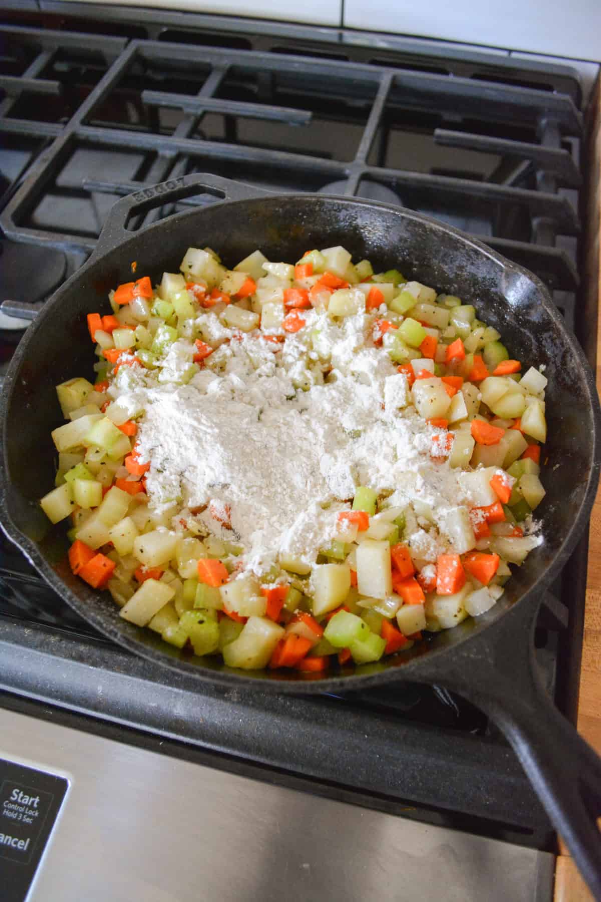 Vegetables cooking in a cast iron skillet topped with flour.