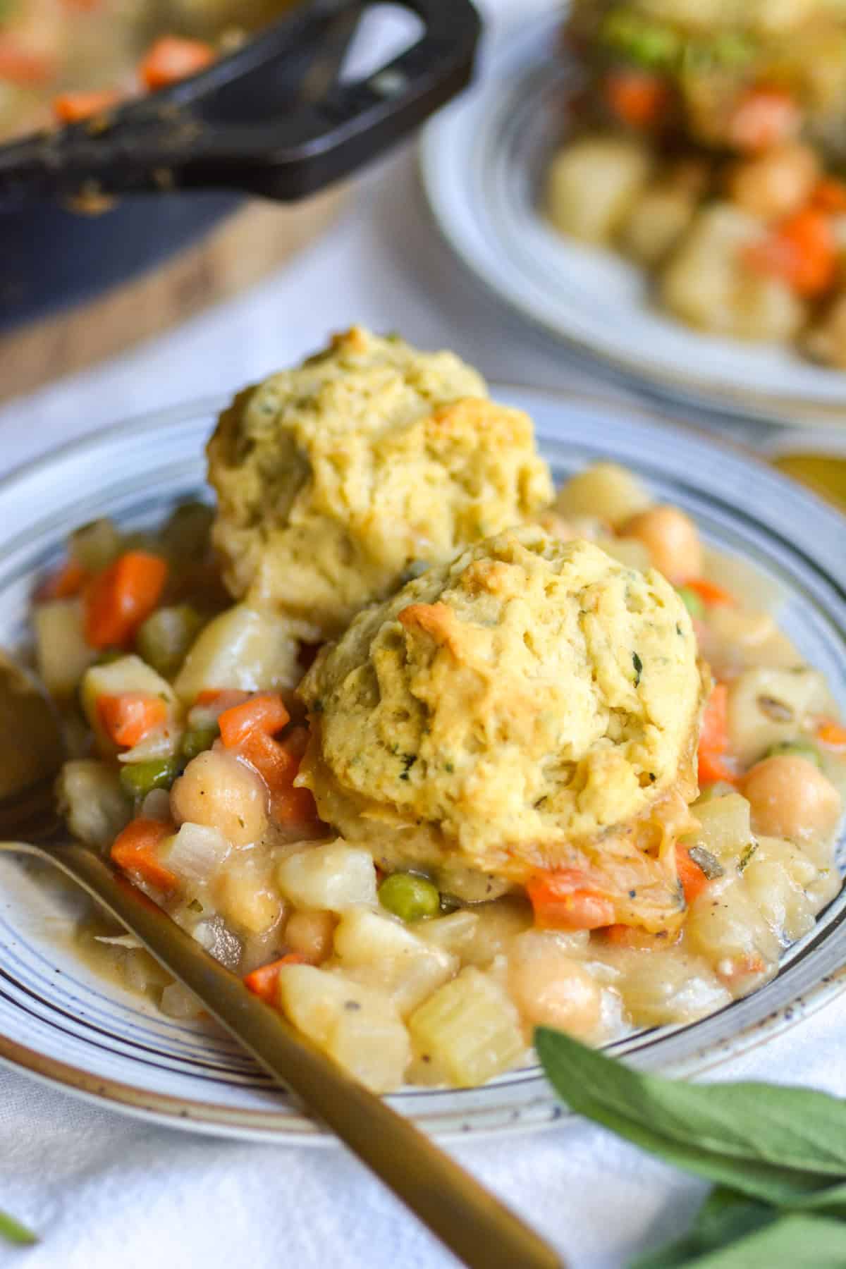 Vegan Chickpea Pot Pie topped with herbed biscuits on a plate with a gold spoon.