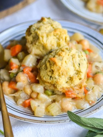 Vegan Chickpea Pot Pie with biscuits on top on a plate with a gold spoon.