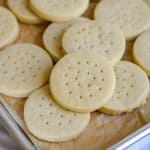 Vegan Shortbread Cookies layered on top of each other on a parchment-lined baking sheet.