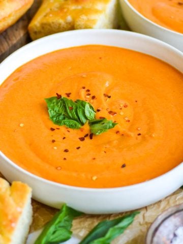 Vegan Roasted garlic tomato Soup in a bowl topped with basil.