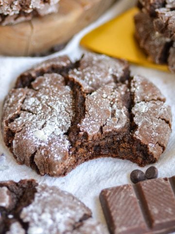 Vegan Gluten-Free Chocolate Crinkle Cookie with a bite taken out of it on a linen cloth.