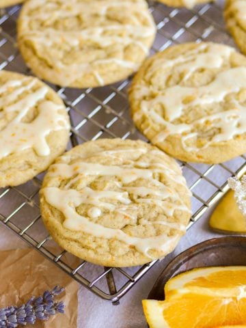 Orange Cardamom Cookies drizzled with orange glaze on a wire cooling rack.