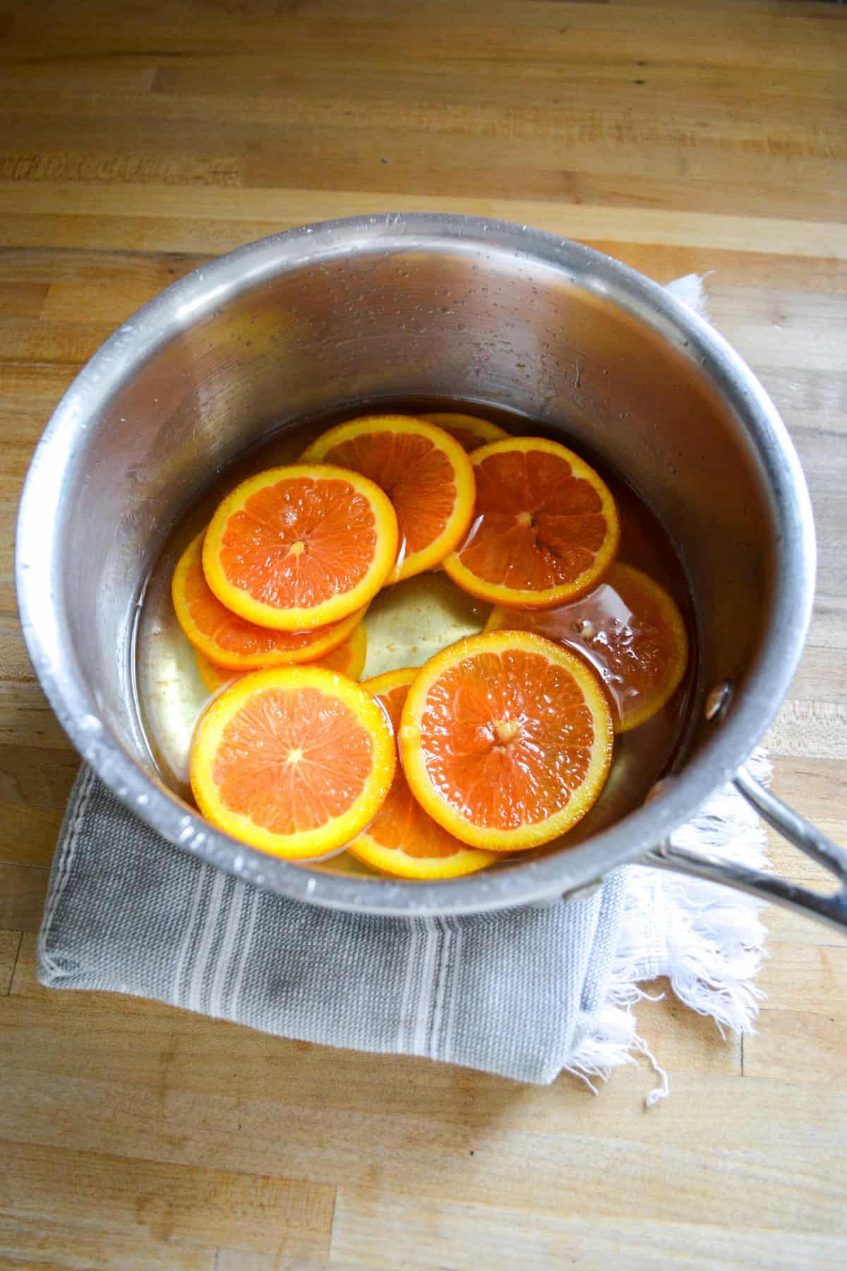 Orange in a pot with simple syrup.