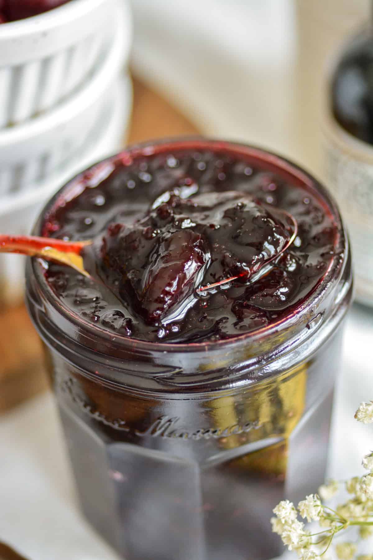 A spoon in a jar of cherry jam.