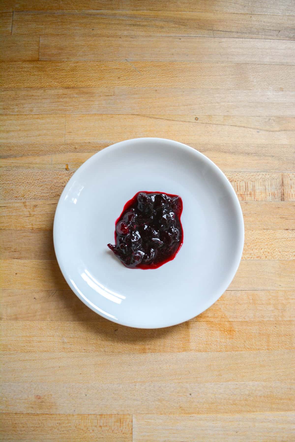 A dollop of jam on a small white plate.