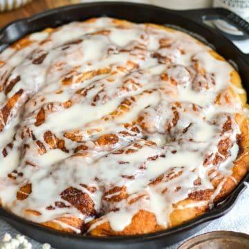 Cinnamon Roll Focaccia drizzled with sweet vanilla glaze in a cast iron pan.