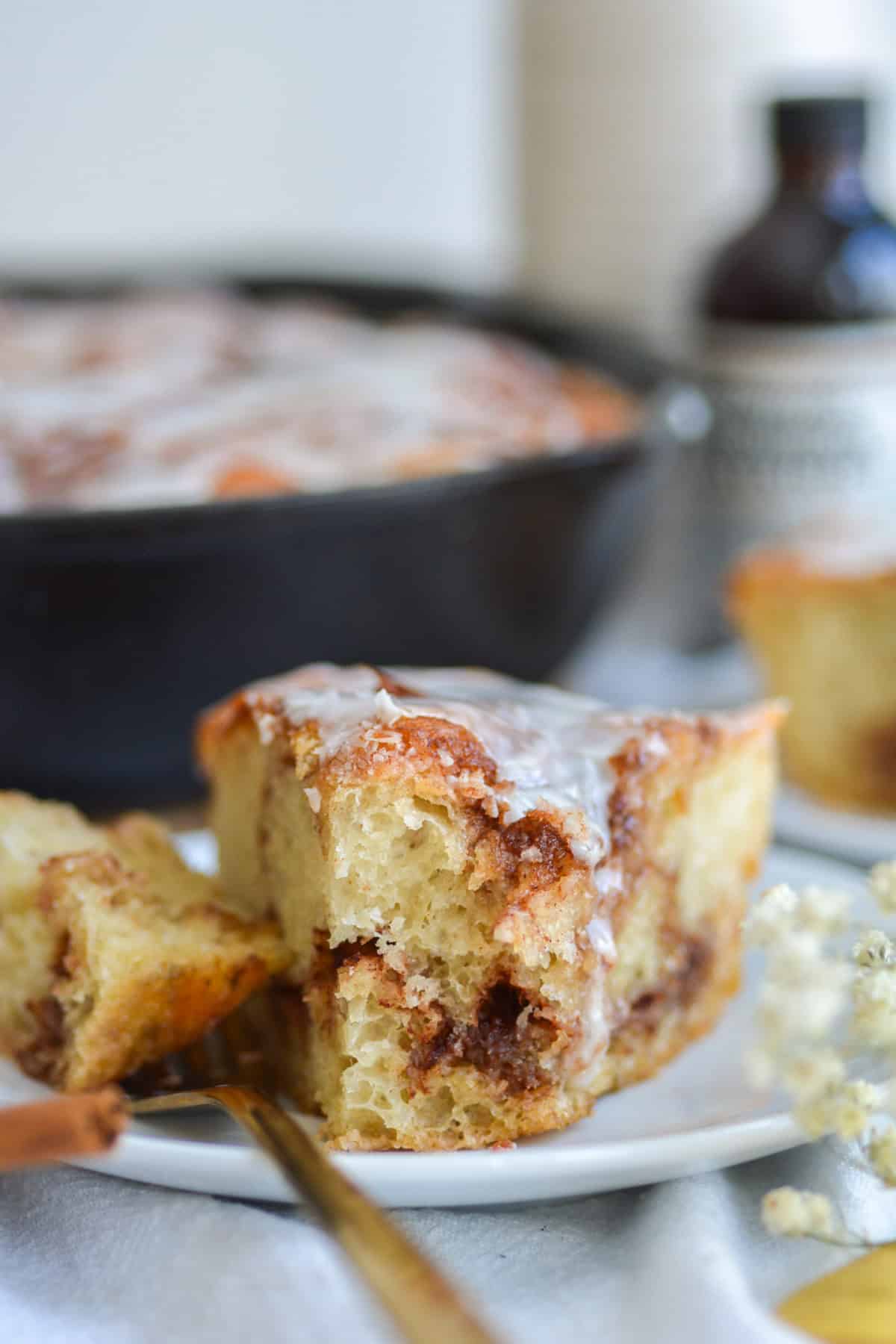 A piece of cinnamon roll focaccia on a plate with a bite taken out of it.