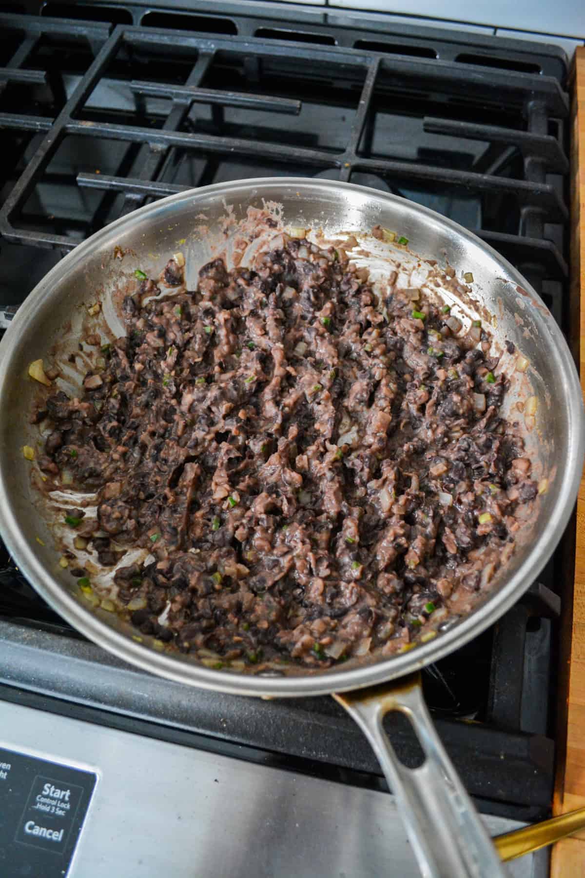 Mashed black beans in a skillet.