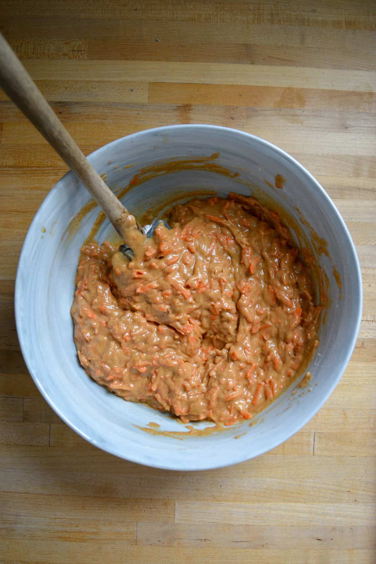 Carrot Cake Muffin batter in a large mixing bowl with a spatula inside.