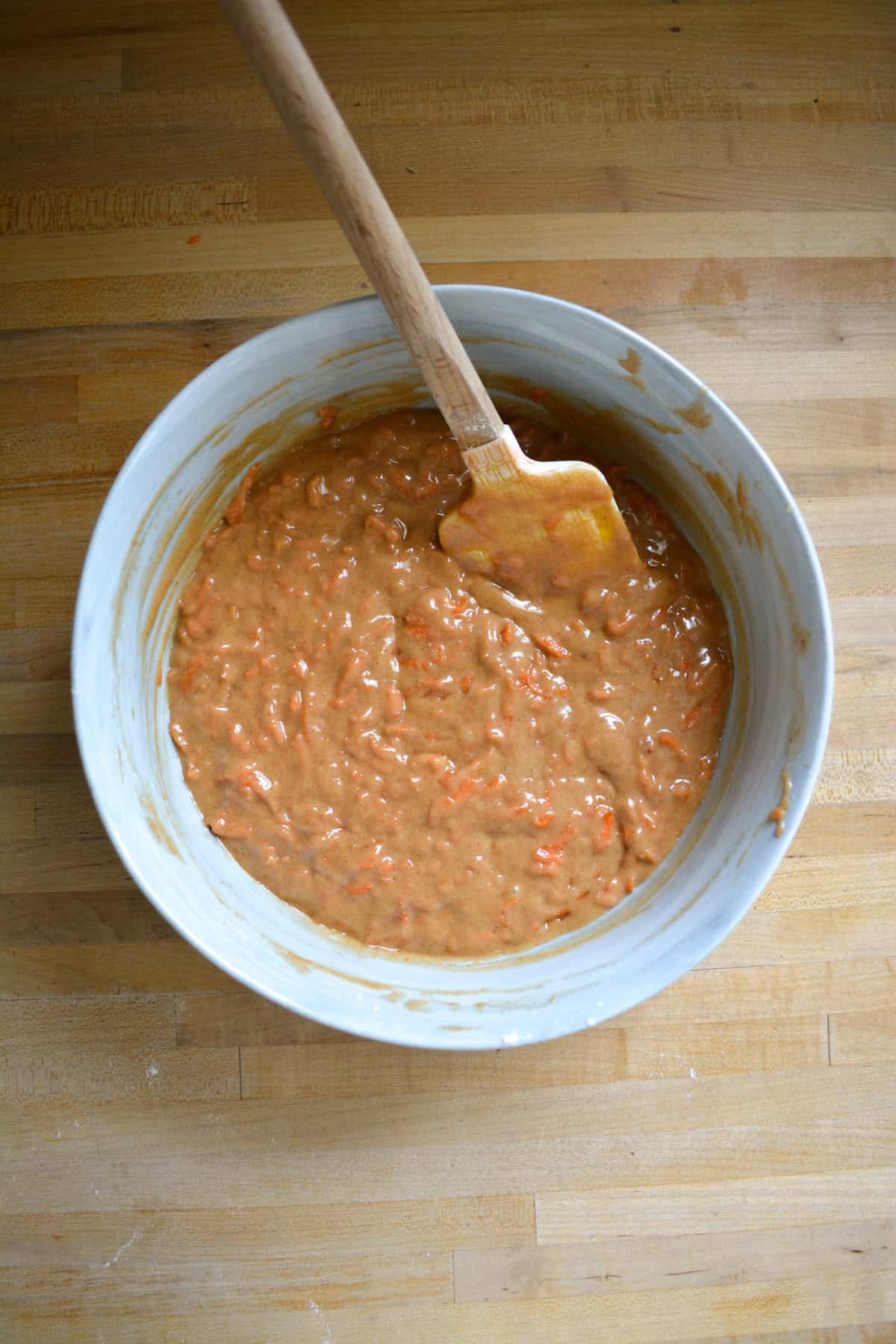 Carrot Cake Loaf batter in a large mixing bowl with a  rubber spatula inside.