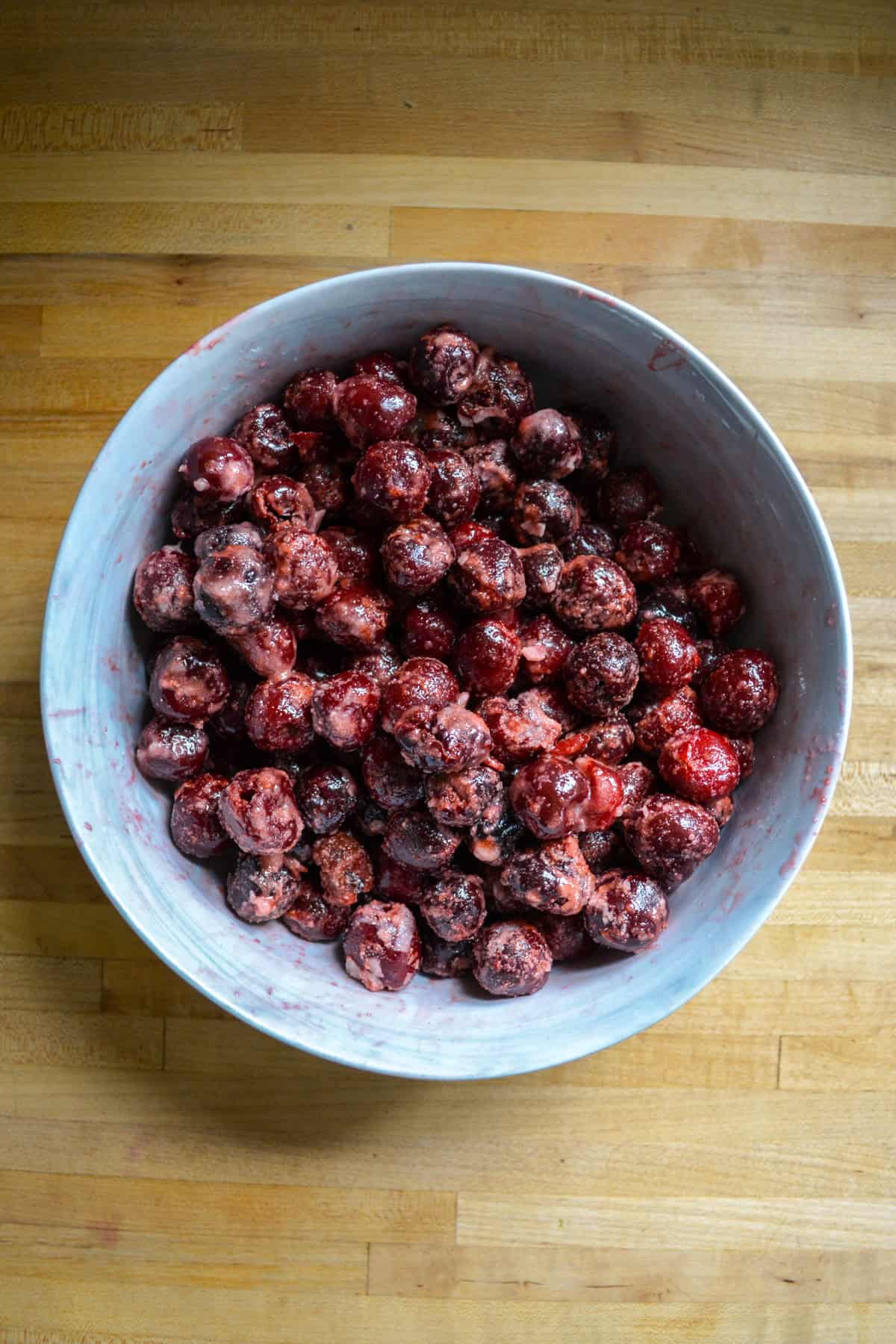 Frozen cherries tossed with sugar and cornstarch in a large mixing bowl.