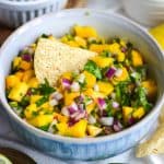 Mango Pico de Gallo in a bowl with a tortilla chip stuck into the salsa.