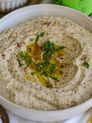 Baba Ganoush in a bowl topped with olive oil and chipped parsley.