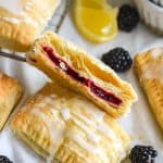 A blackberry hand pie with puff pastry cut in half to show the the interior.