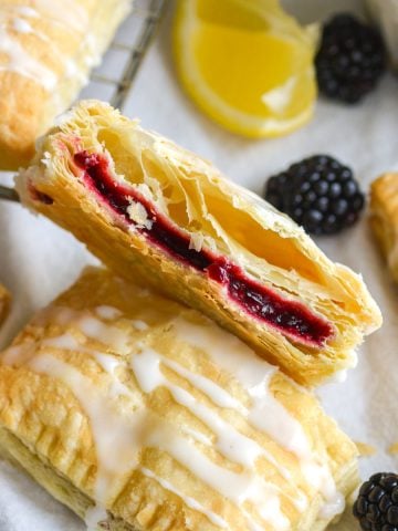 A blackberry hand pie with puff pastry cut in half to show the the interior.