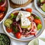 Greek Village or Horiatiki Salad topped with feta cheese chunks on a small plate.