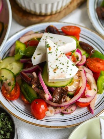 Greek Village or Horiatiki Salad topped with feta cheese chunks on a small plate.