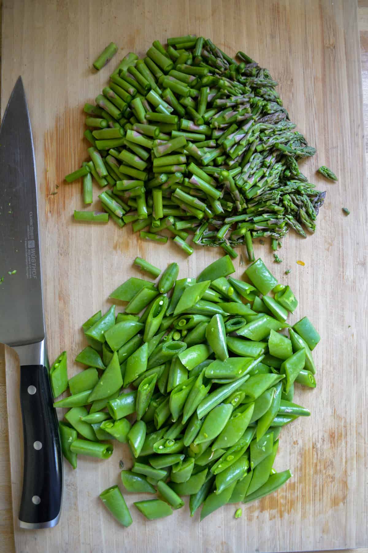 Chopped snap peas and asparagus on a cutting board.