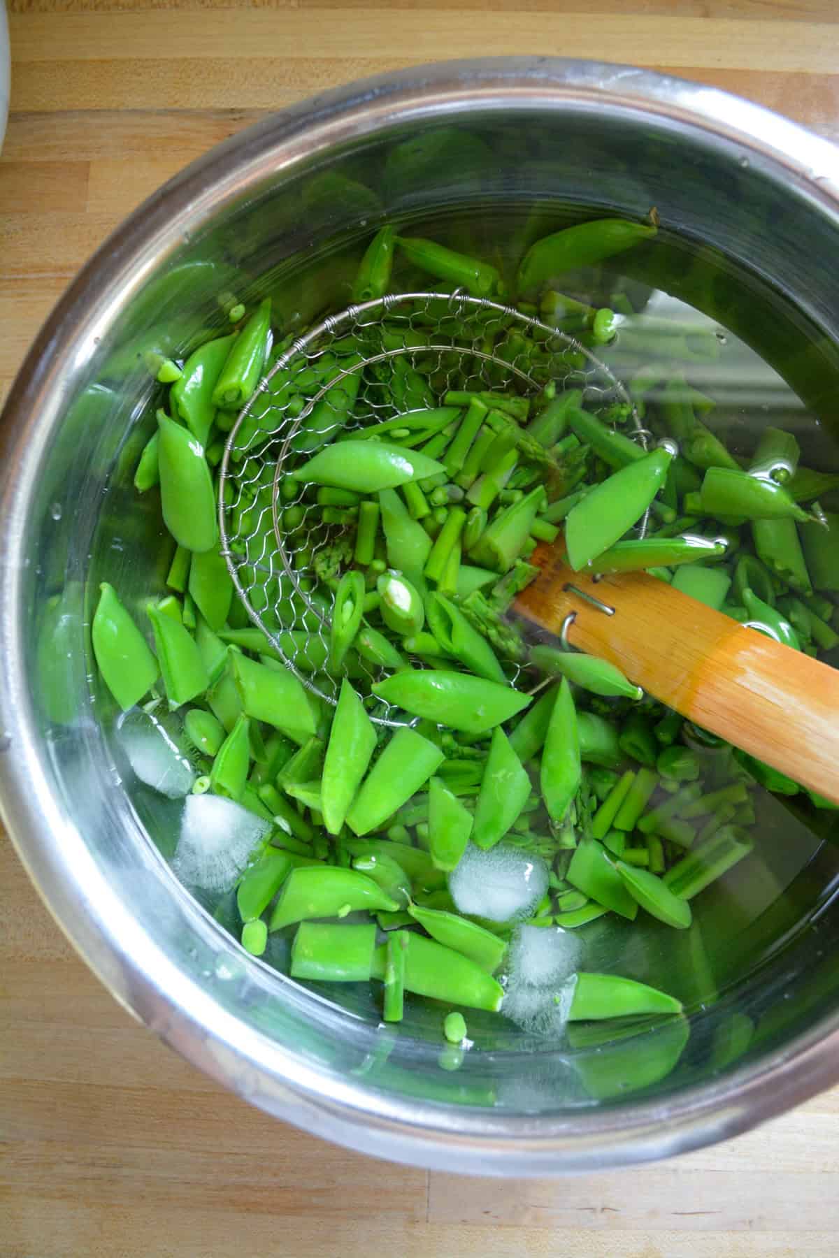Asparagus and snap peas in an ice bath.