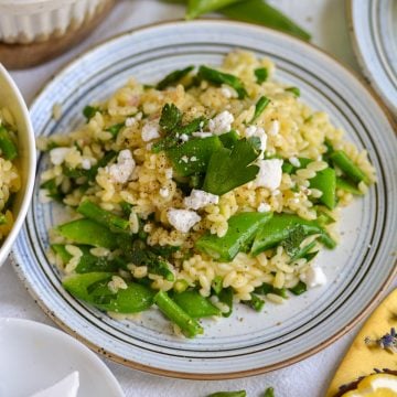 Lemon Orzo Pasta Salad on a plate topped with feta cheese and parsley.
