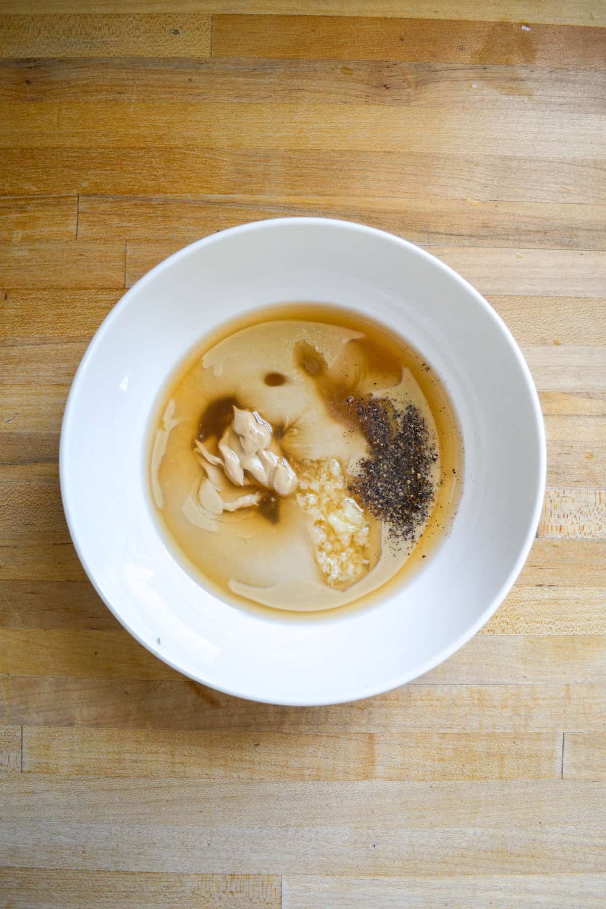 Ingredients in a medium bowl on a wooden surface.