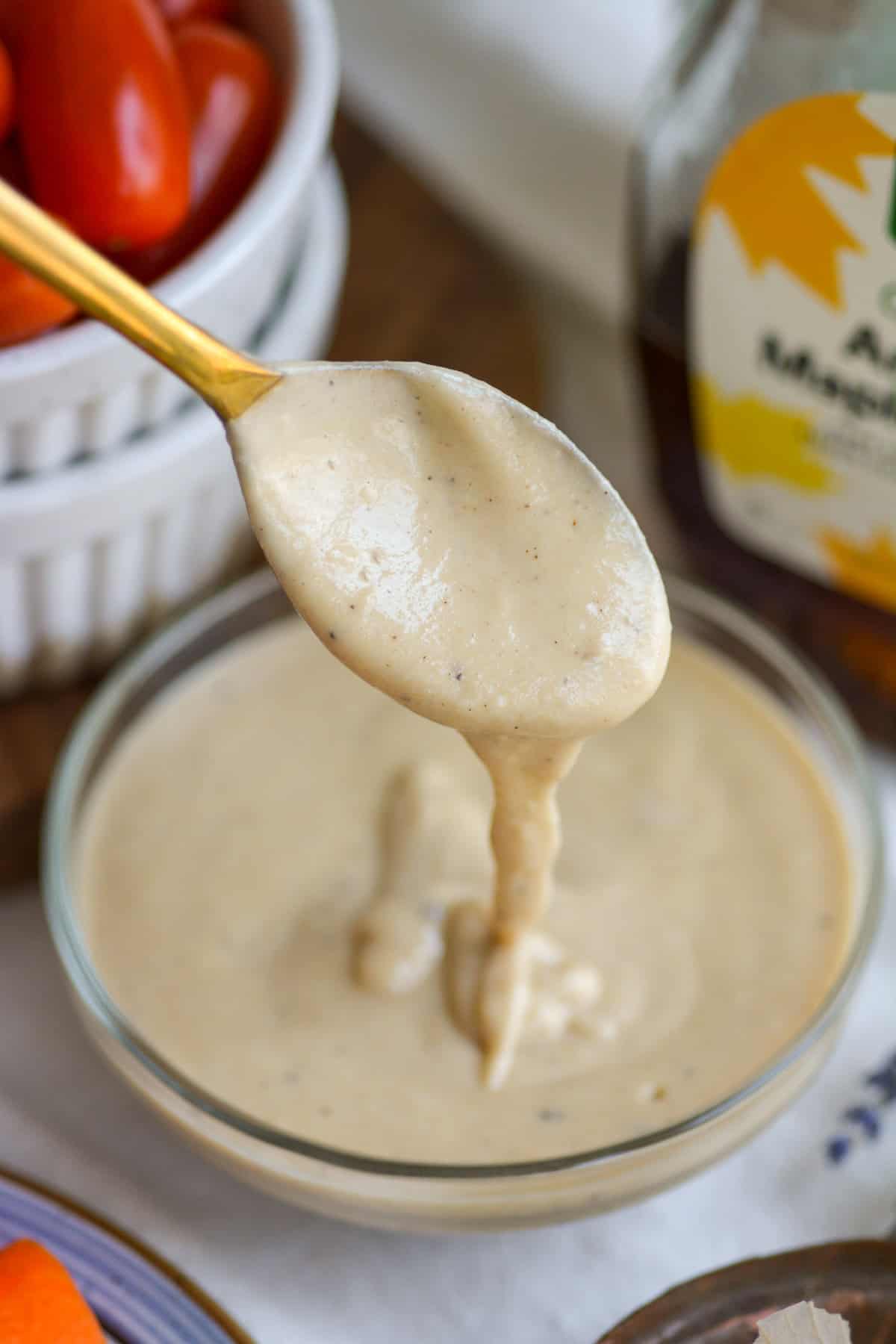 Spoon with Maple Tahini Dressing drizzling off of it.