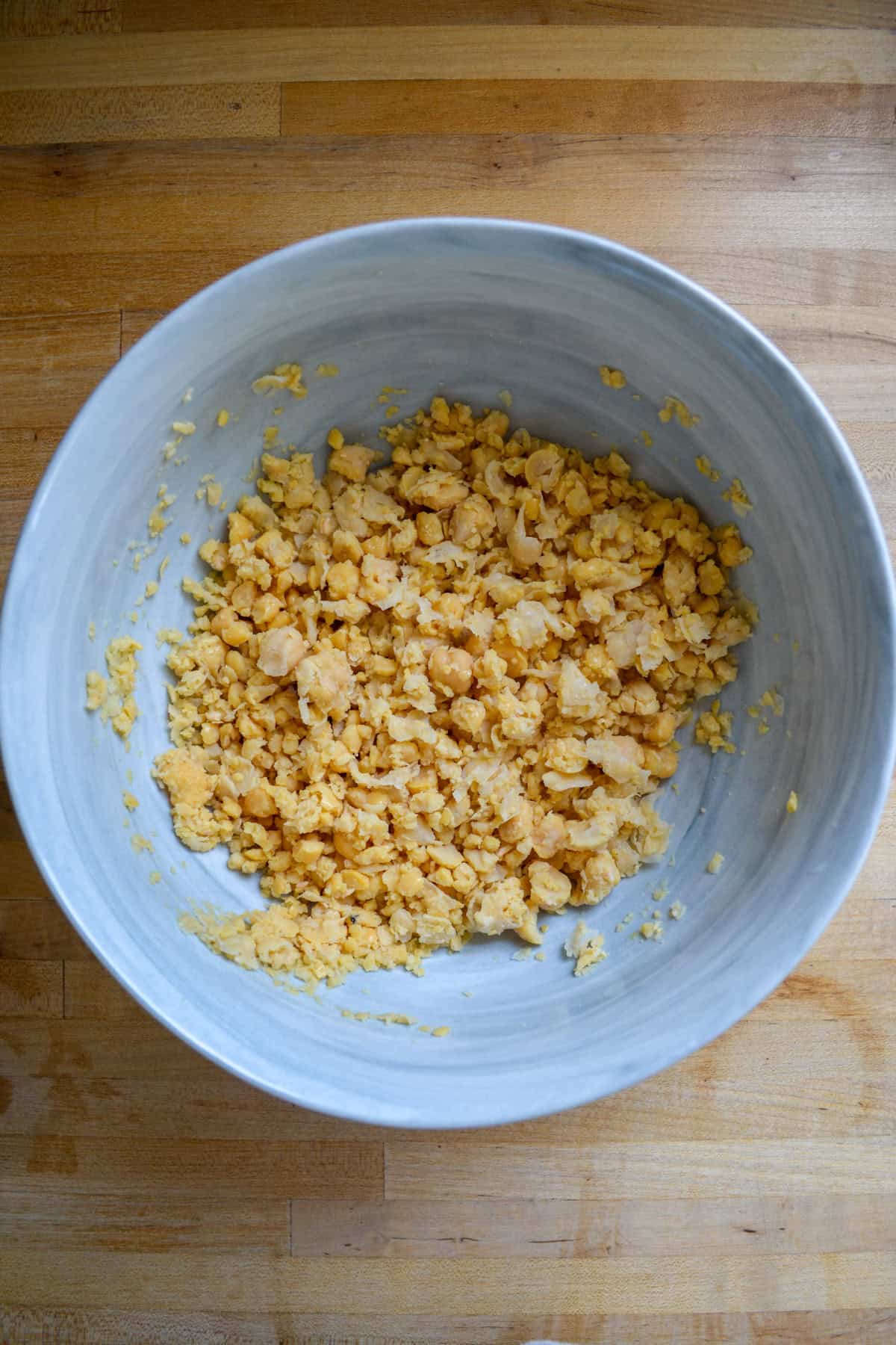 Smashed chickpeas in a large mixing bowl.