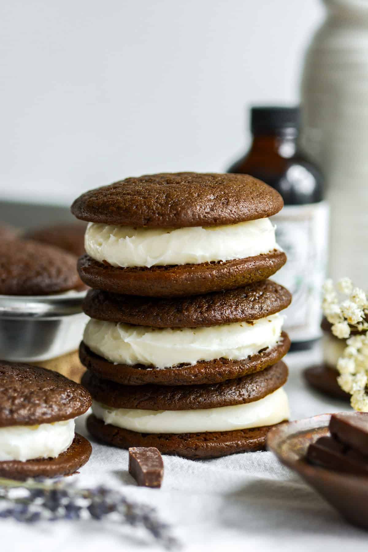 Three Vegan Chocolate Whoopie Pies stacked on top of each other on a linen cloth.