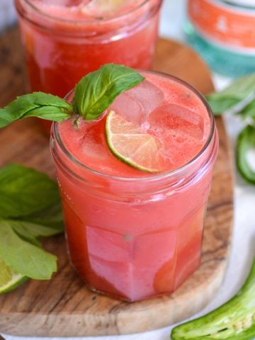 Watermelon Vodka Cocktail in a glass on a small wooden cutting board.
