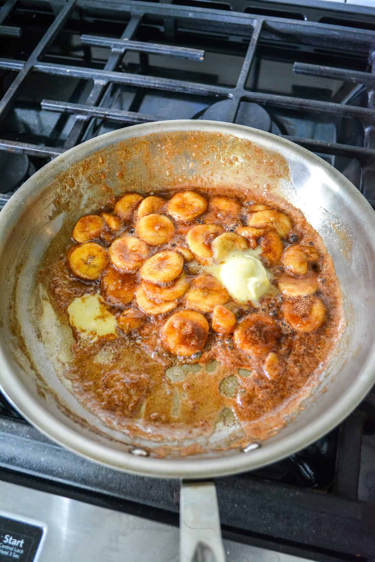 Bananas and butter added to the skillet with maple syrup.