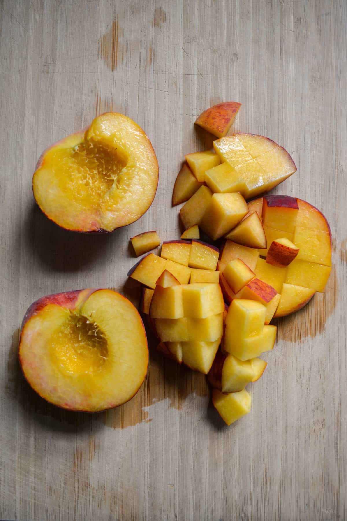 Chopped peaches on a wooden cutting board.