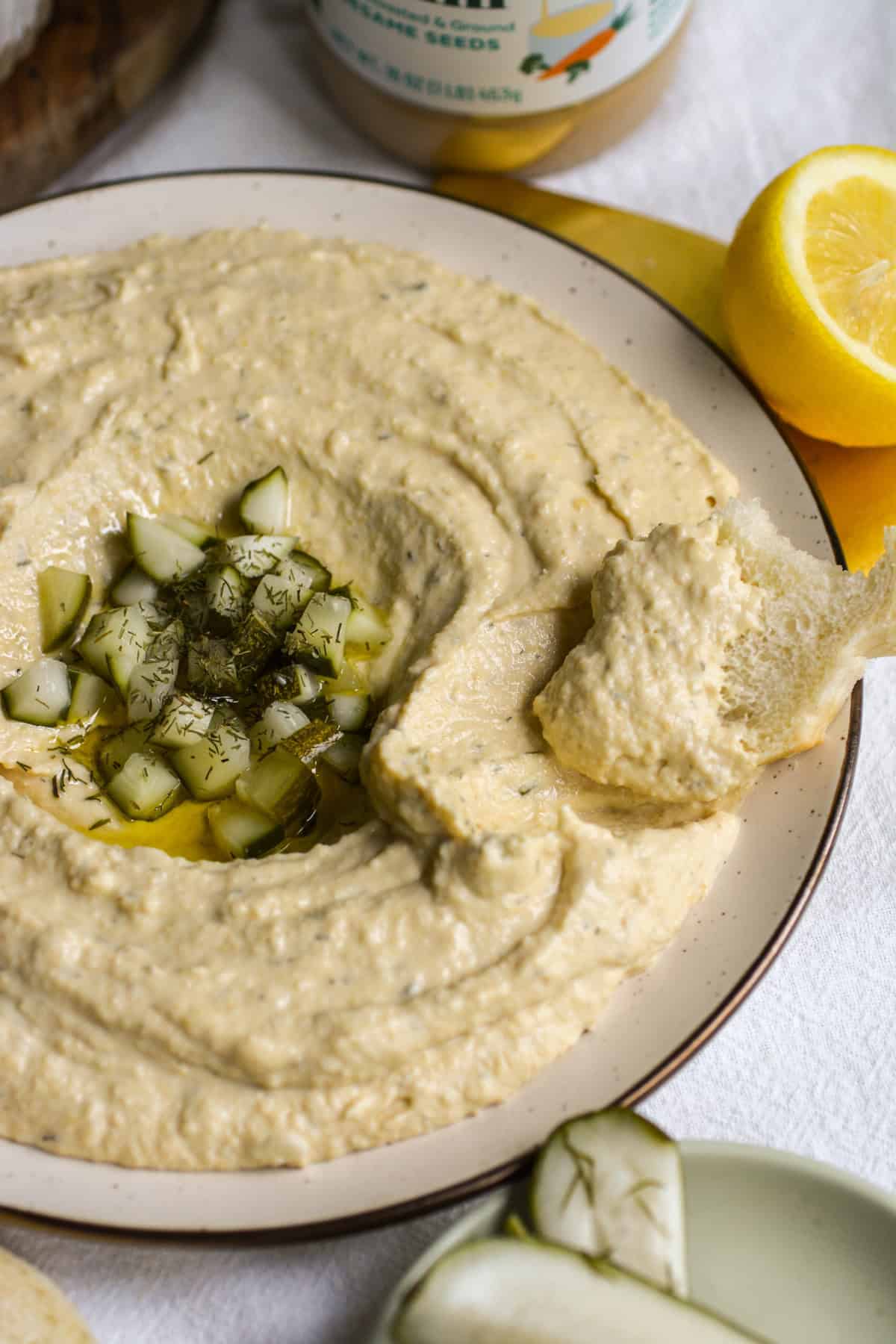 A piece of bread dipped into Dill Pickle Hummus.