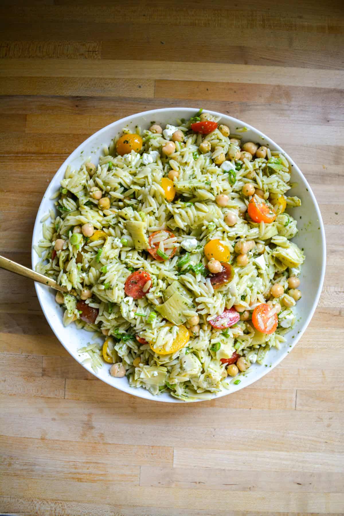 Pasta salad tossed together in a large bowl.