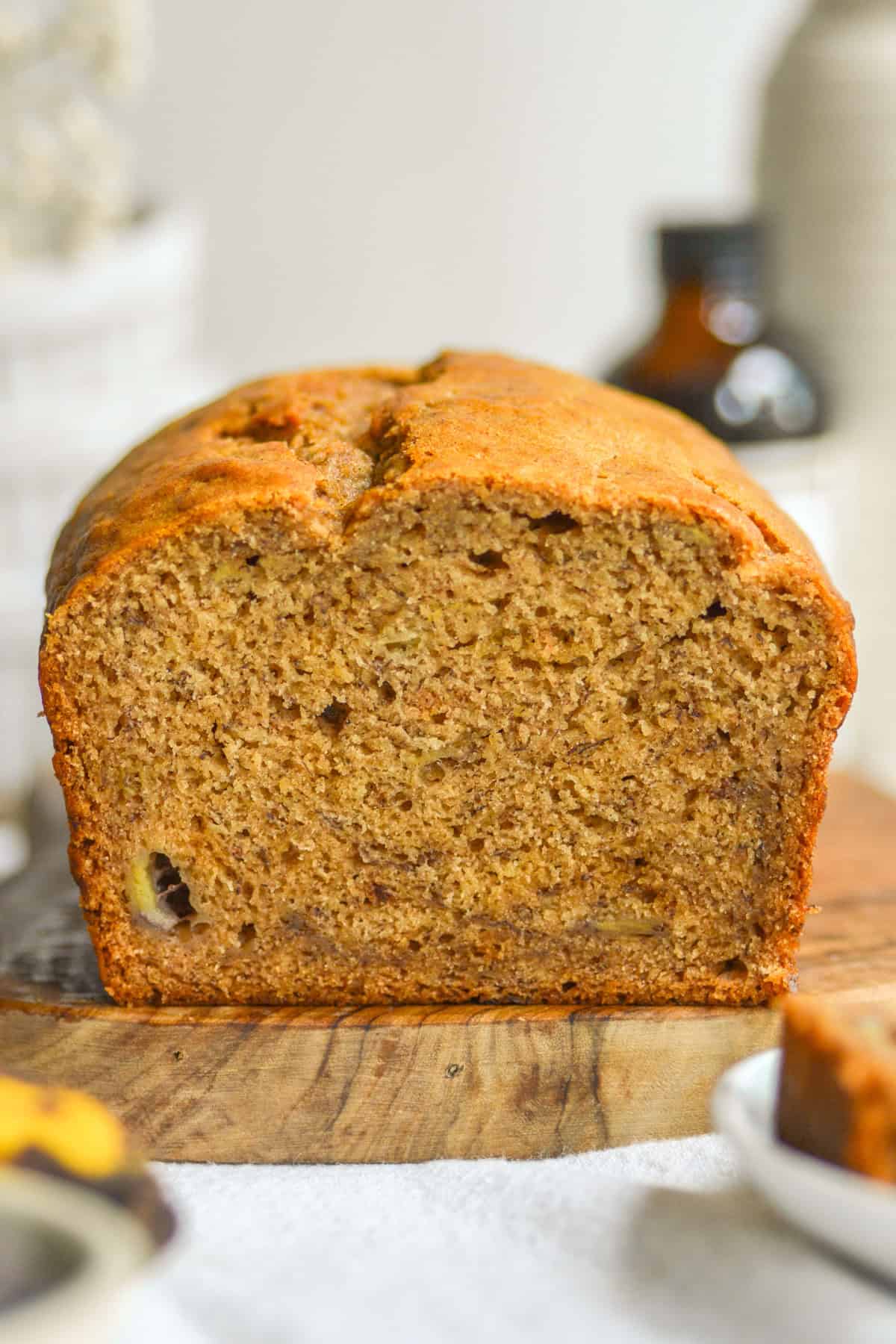 A loaf of Vegan Banana Bread with on a small wooden cutting board.
